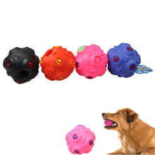 Four colorful puppy teeth cleaning balls in black, red, pink, and blue, with textured surfaces, are displayed alongside a dog.