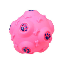 Bright pink, rubber puppy teeth cleaning ball with textured surfaces and blue paw print accents.